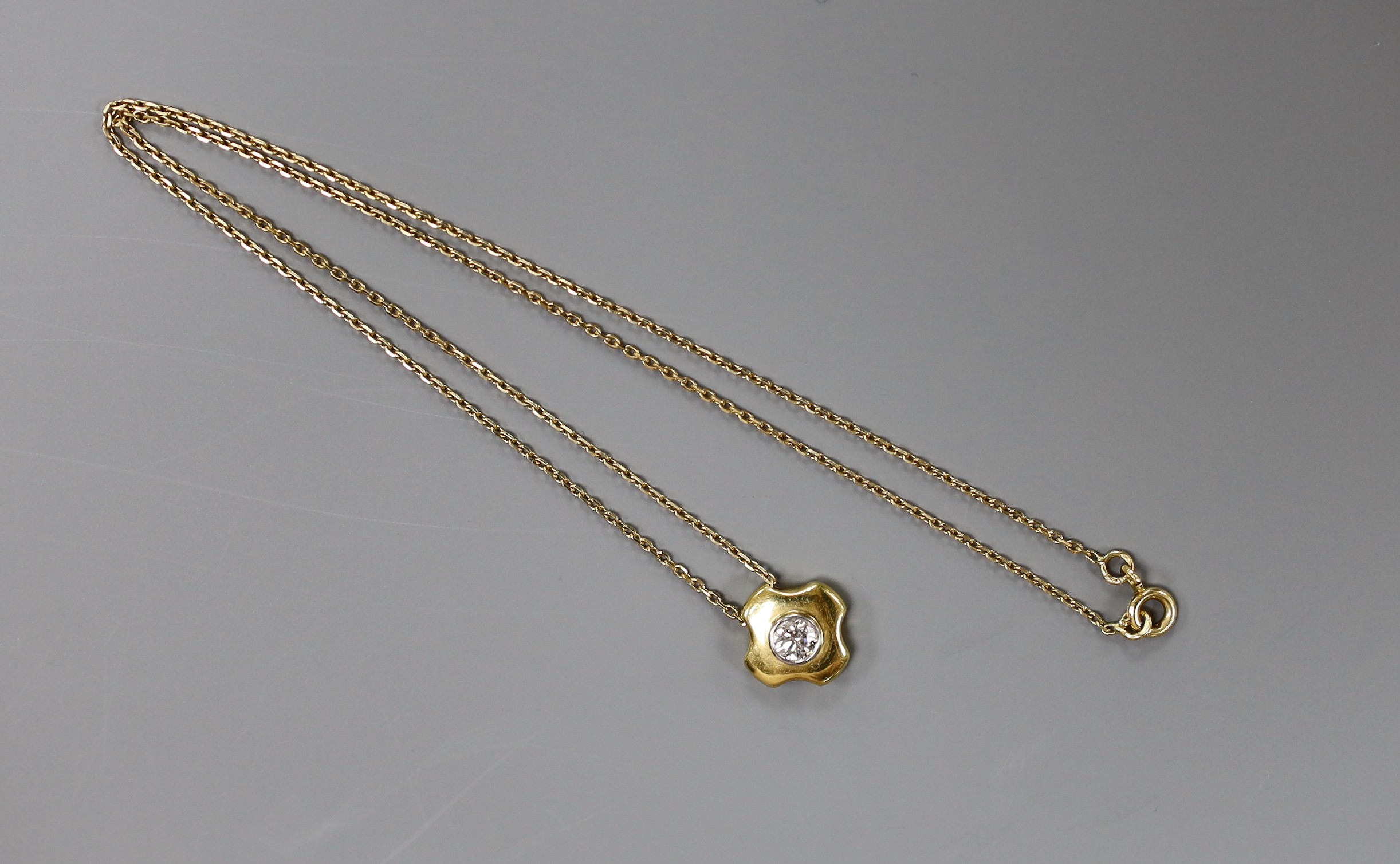 A modern 18ct gold and single stone diamond set quatrefoil pendant, 7mm, on an 18ct gold fine link chain, 38cm, gross weight 6 grams